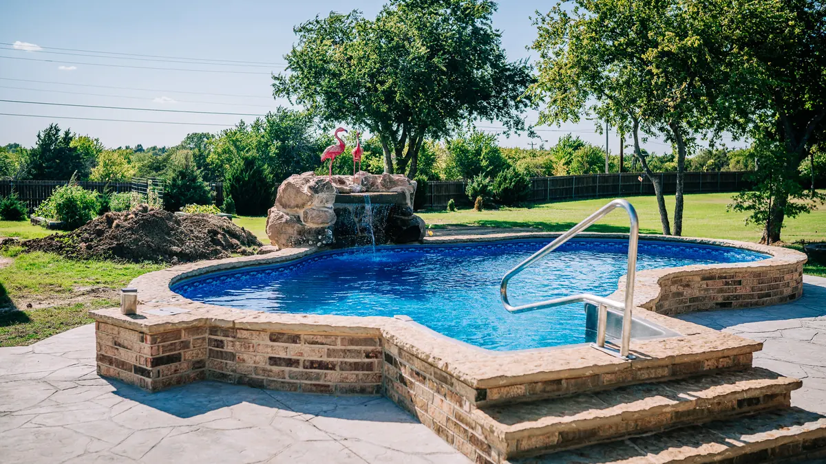 Vinyl liner pool with brick raised wall and rock waterfall in Oklahoma
