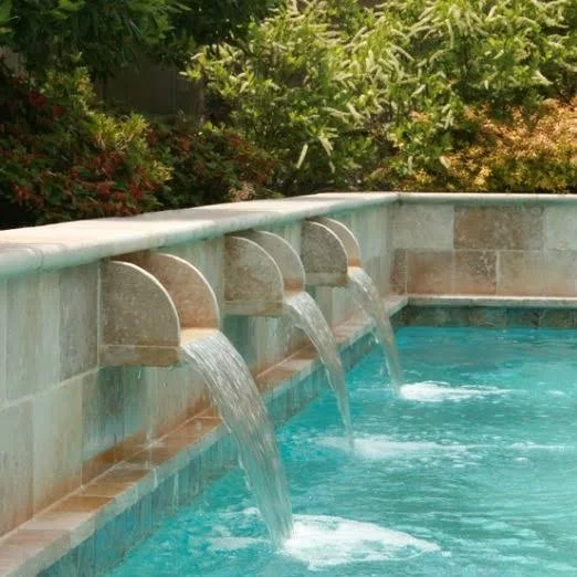 Stone scuppers pouring water into a pool